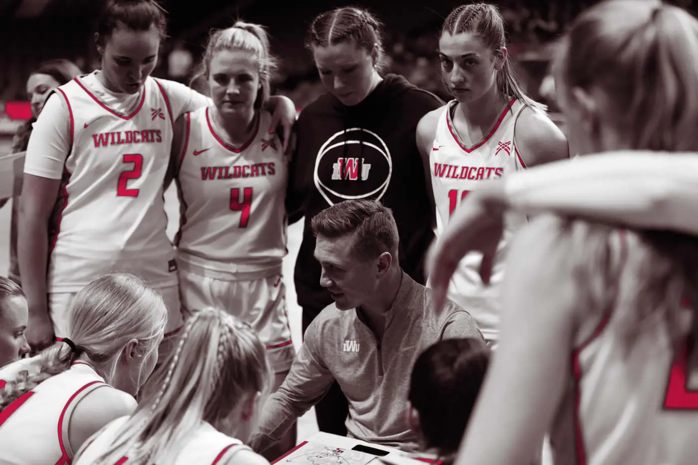 Female basketball players in a huddle with the coach